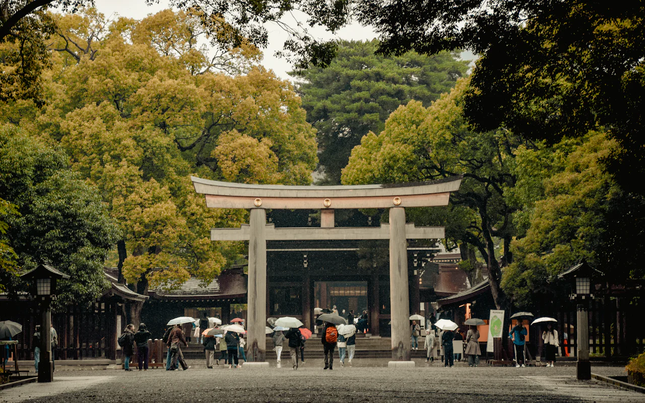 傘をさした人たちが歩く大きな鳥居の参道