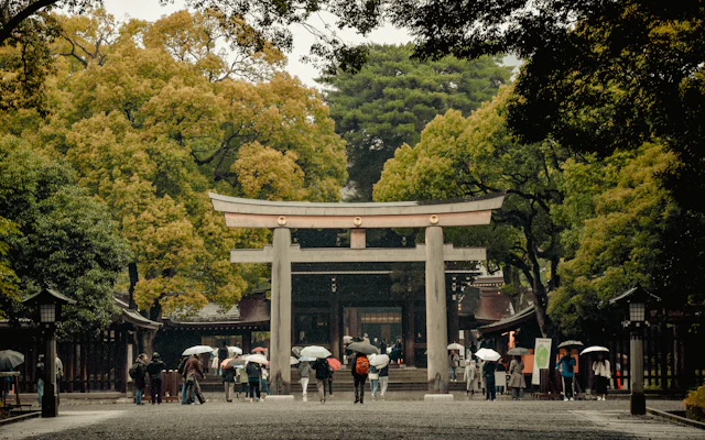 傘をさした人たちが歩く大きな鳥居の参道