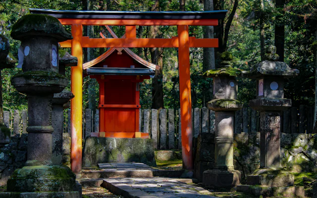 石灯籠の奥に立つ赤い鳥居と小さな社